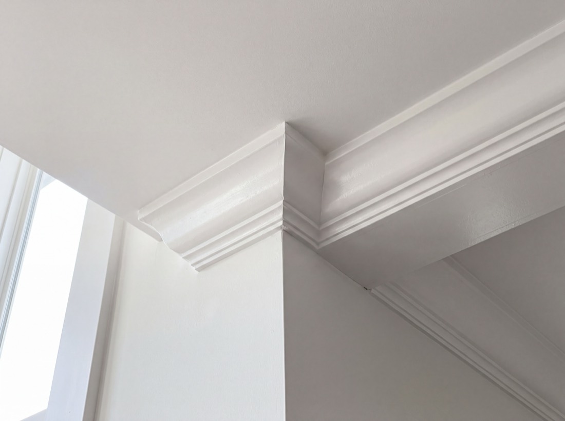 Two runs of painted crown molding meeting in a mitered inside corner